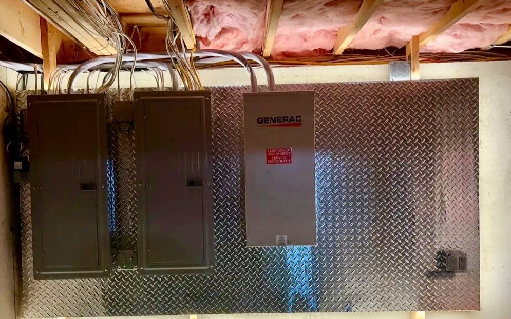 Generac transfer switch beside two breaker panels on a diamond-plate backboard