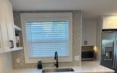 Remodeled kitchen with a tiled backsplash, outlets and a switch beside the window over the sink
