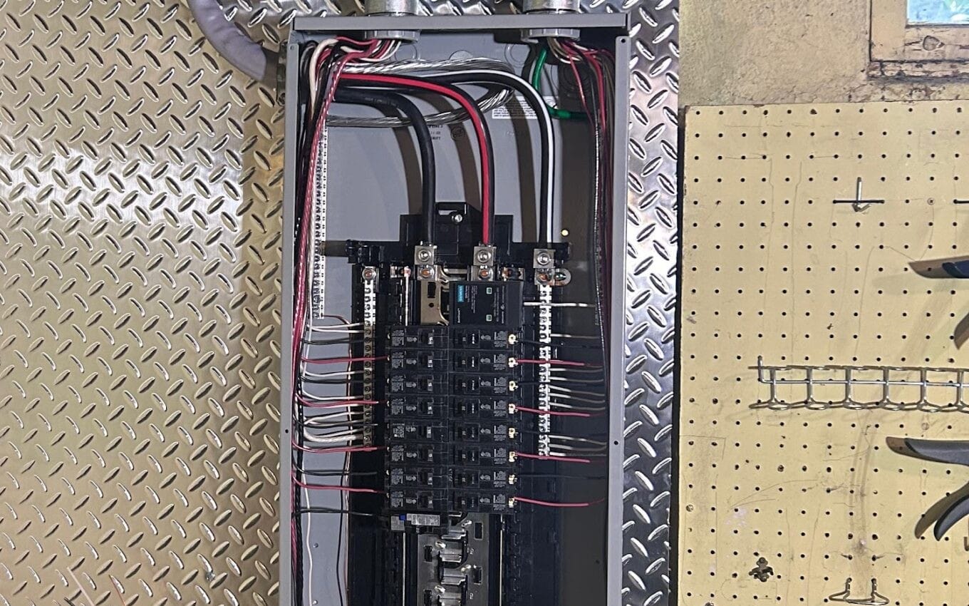 New breaker panel with branch circuits landed and the cover off, on a diamond-plate backboard