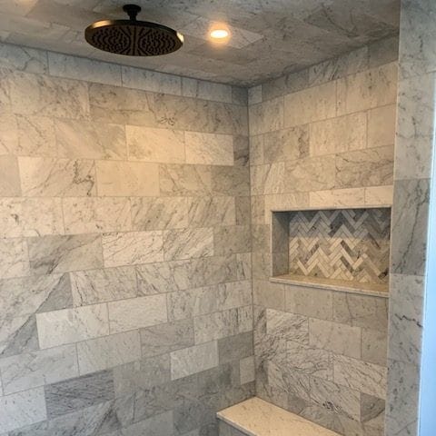 Marble-tiled shower with a ceiling rain head and a recessed shower light