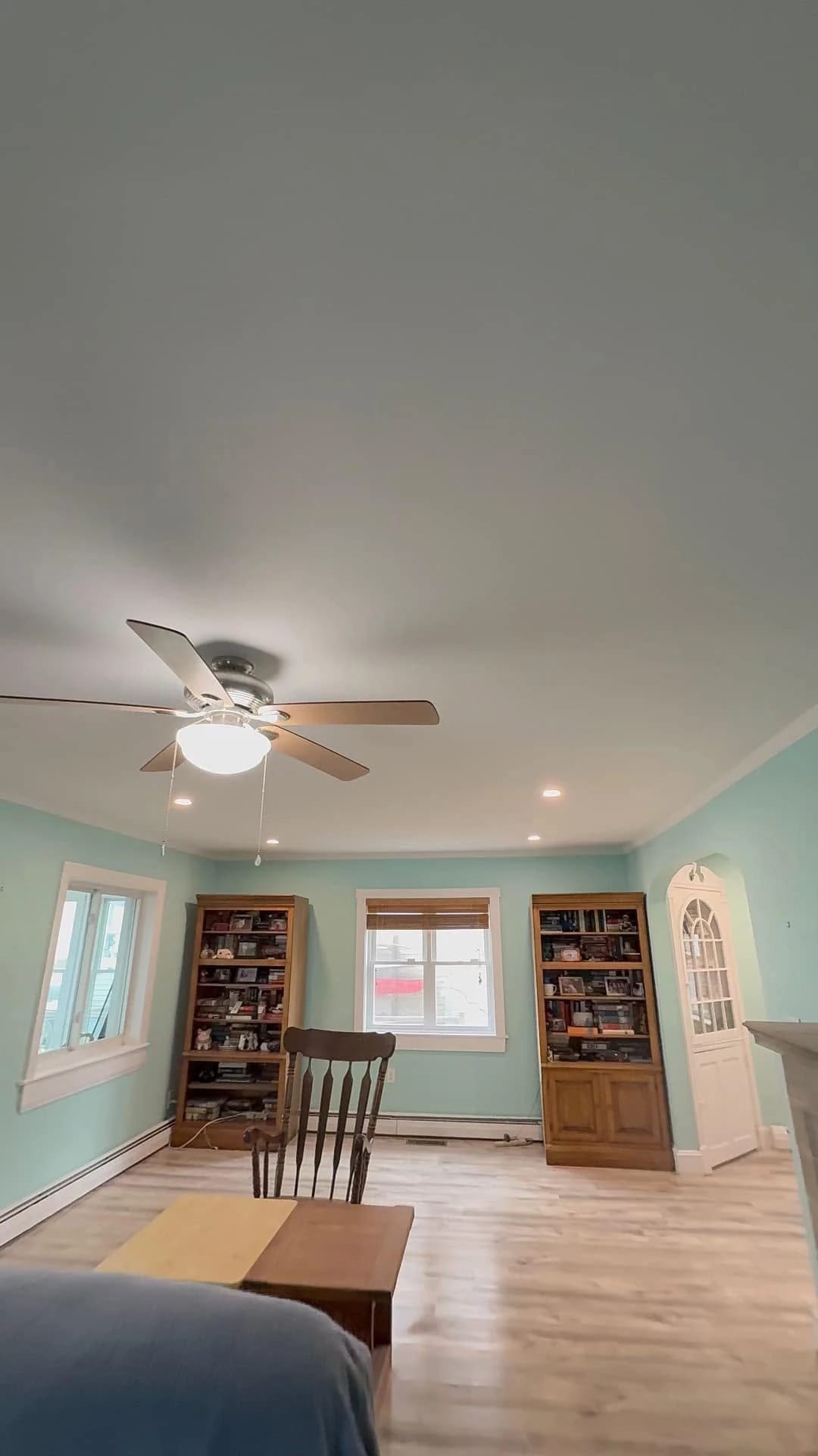 Ceiling fan with a light kit and recessed lights in a freshly painted living room, installed by Colonial Electric