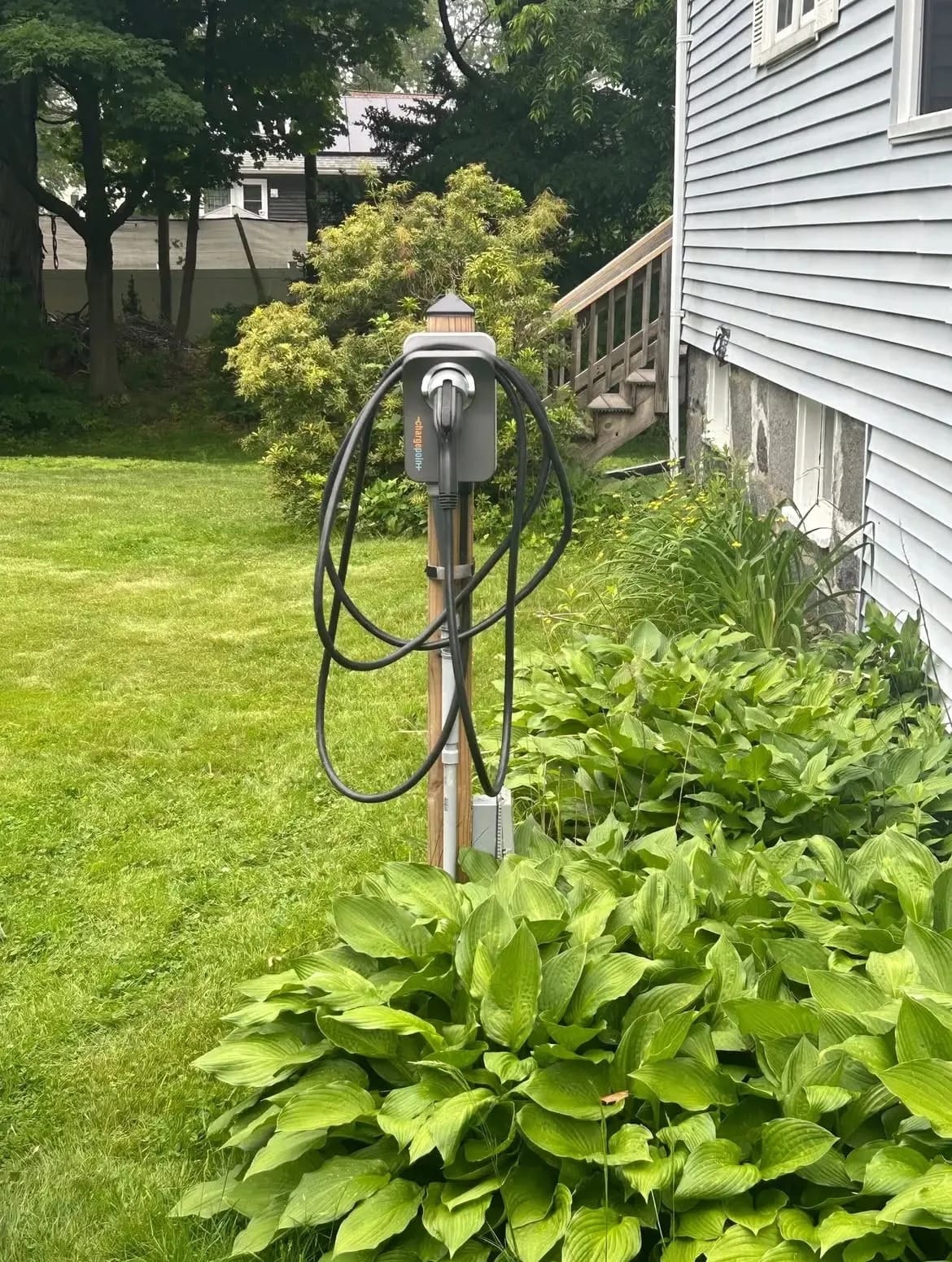 ChargePoint home EV charger mounted on a cedar post beside a house, installed by Colonial Electric