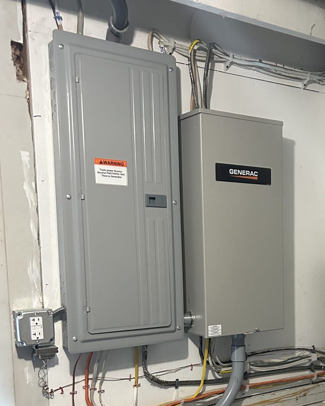 Generac transfer switch mounted beside a breaker panel labelled for generator power, installed by Colonial Electric