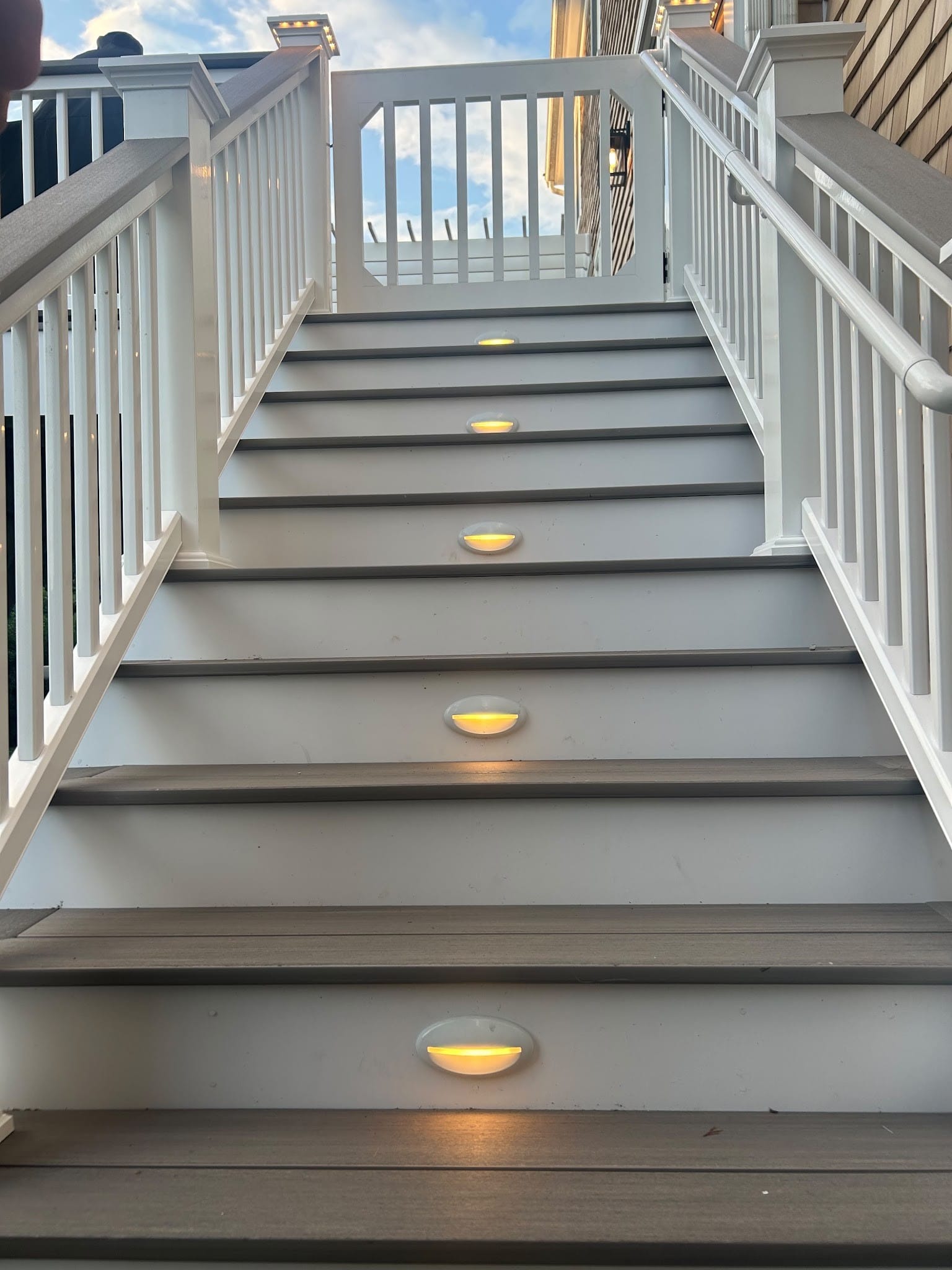 LED step lights set into the risers of a white deck stair, a Colonial Electric job
