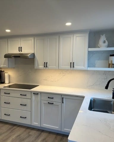 Remodeled kitchen with recessed ceiling lights over white shaker cabinets and a lit quartz backsplash, a Colonial Electric job